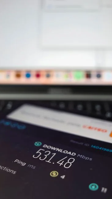 Close-up shot of an orange credit card held above a laptop, highlighting digital payment.